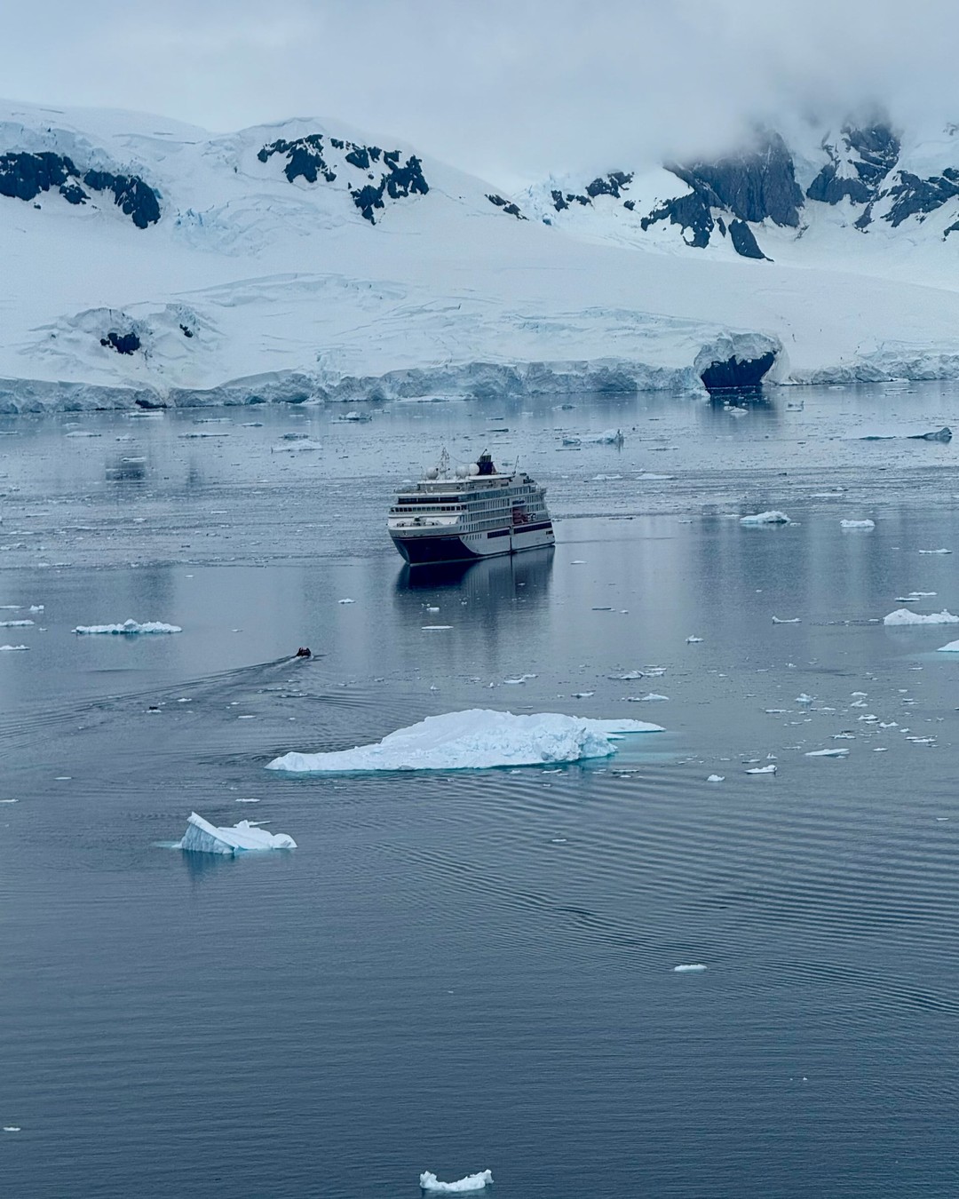 Expeditionsschiff vor Eisberg in polarer Landschaft